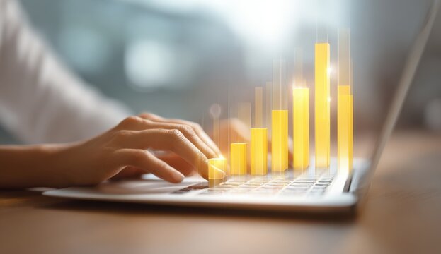 Close-up of a person's hand typing on a laptop with rising bar chart in the