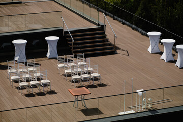 Minimalist rooftop terrace prepared for outdoor event with white chairs and tables