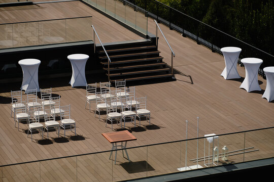 Minimalist rooftop terrace prepared for outdoor event with white chairs and tables
