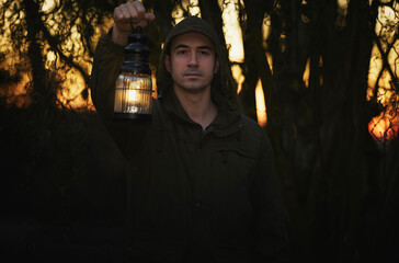 Male portrait in military clothing in a night forest with antique lamp