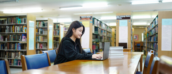 Young college woman working on his computer while studying in the library alone.