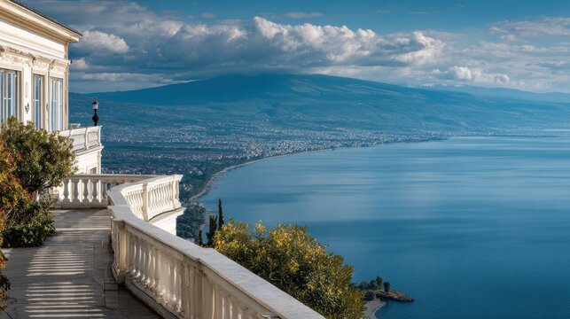 Mansion balcony overlooks a coastal city and vast blue sea.
