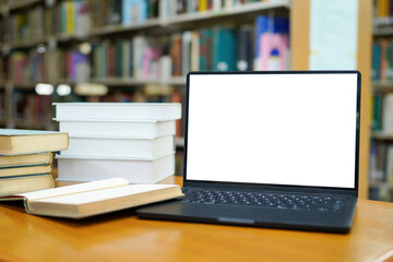 Laptop display surrounded by books in library learning and education concept