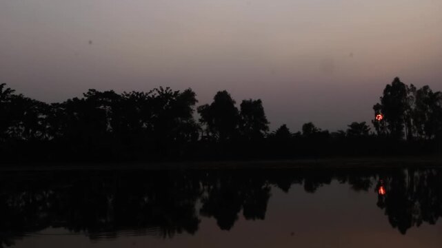 The sun floats in the sky above the big tree. Good and beautiful reflect with silhouette all around. The sun floats in the sky above the big tree. Shining light on the surface morning.