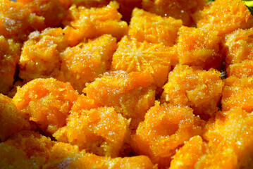 Square pieces of orange sponge cake dusted with sugar. Close-up of treats served at the Orange Festival in Herceg Novi, Montenegro. Symbolizes local gastronomy, handmade dessert, community celebration