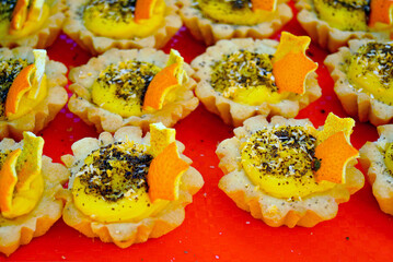 Mini tartlets with orange cream, sprinkles, and decorative stars. Concepts of creative food styling, edible craftsmanship, artistic presentation, craft bakery aesthetics and joyful festive culture.