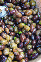 Close-up of glossy marinated mixed olives with herbs and garlic. Mediterranean antipasto staple. Concept of savory appetizer ingredient, healthy monounsaturated fat source, authentic regional delicacy