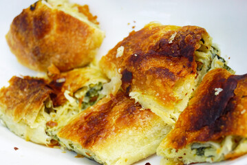 Traditional Balkan cuisine — burek with greens. A signature dish of Serbia, Montenegro, and Bosnia and Herzegovina, made from filo pastry. Authentic regional gastronomy and slow food concept.