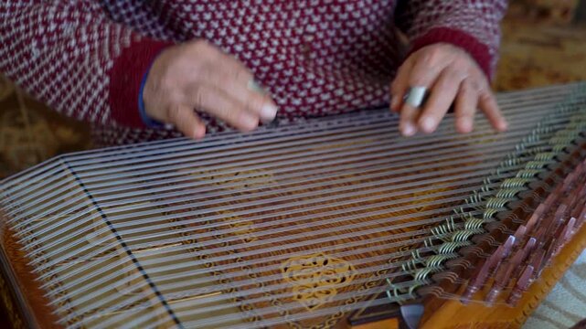 old man playing traditional turkish instrument qanun