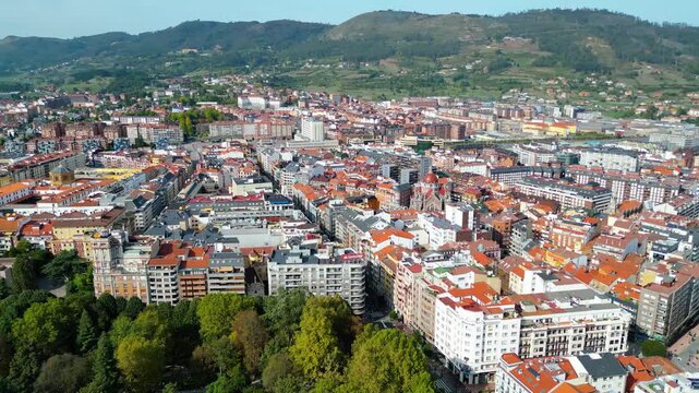 Aerial view of Oviedo, Spain, showcasing the vibrant Parque de San Francisco amidst historic architecture and distant mountains. A beautiful autumn afternoon.