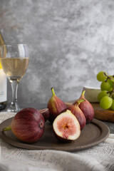 カットされたイチジクの盛られたお皿と、シャインマスカット、チーズ、ワインがテーブルに並んでいる
