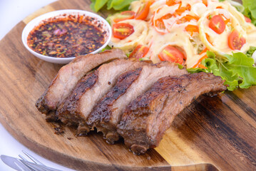 Roasted pork steak with dry chili dipping sauce on the wooden plate.