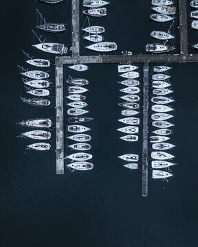 Aerial view of the marina's neat rows of white boats contrast dramatically with the deep blue sea, creating a serene yet structured tableau, Trieste, Friuli-Venezia Giulia, Italy.