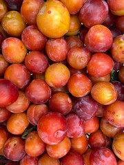 Fresh ripe plums with vibrant red and orange hues forming a colorful fruit background