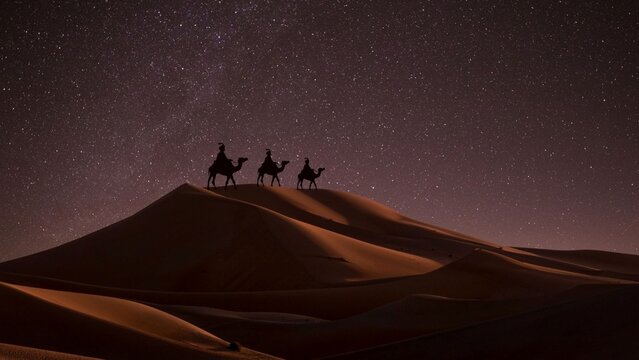 Los Tres Reyes Magos siguiendo la Estrella de Bel&eacute;n &mdash; Melchor, Gaspar y Baltasar cruzando el desierto en la noche estrellada, montados en camellos y guiados por la luz celestial.