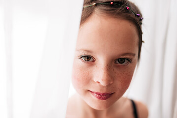Close-up Portrait of a young girl wearing make-up standing by a curtain