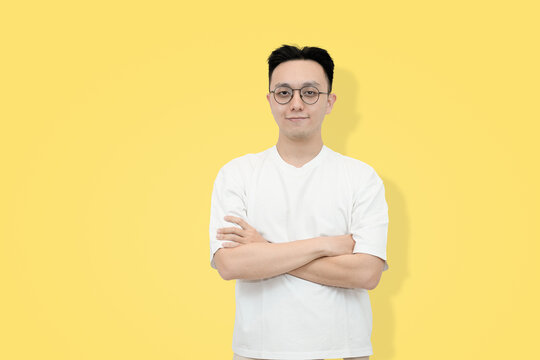 A young Asian man stands confidently against a yellow background