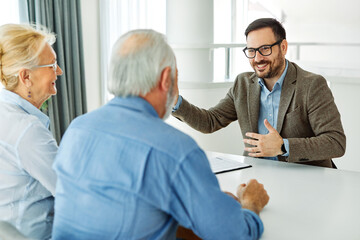 Obraz premium Senior couple having a meeting with an agent, businessman, salesperson or doctor in his office
