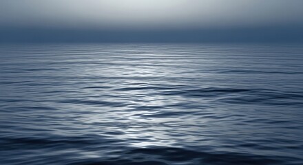 Obraz premium Calm and serene ocean waves ripple gently under a hazy blue sky, creating a tranquil and peaceful seascape.