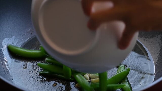 Stir fried garlic and green pea in cooking pan, Asian vegetarian food
