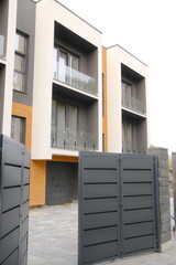 A building exterior features balconies and a large dark gate.
