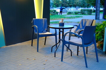 Empty seats await customers at a cafe along the street in the early evening.