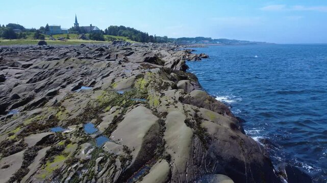 The rocky shore of the St. Lawrence River, formed of sedimentary rocks of Appalachian sandstone dotted with algae, or small waves tickle the rocks. Sainte-F&eacute;licit&eacute;, Quebec, Canada.