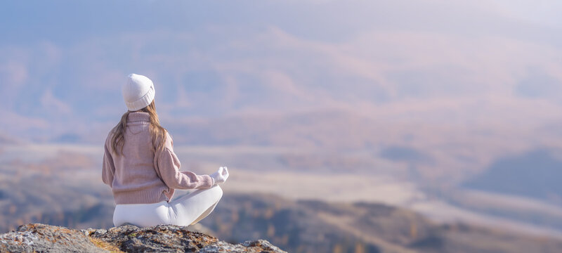 Woman practicing yoga meditation surrounded by autumn mountains in peaceful nature, copy space
