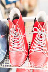 Baby shoes on the floor.A vibrant collection of handmade leather boots in bold green, blue, and red hues displayed on a shelf. Artistic stitching and contrasting laces emphasize fashion, creativity
