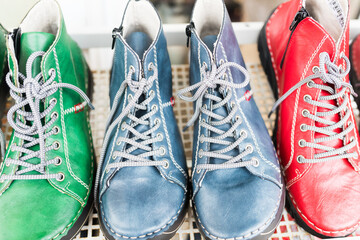 Pair of shoes.Colorful leather boots in green, blue, and red arranged in a row on a store display. Handmade craftsmanship, stylish design, and bright laces highlight their unique and modern character.