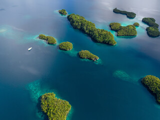 Aerial view of tropical islands and coral reefs surrounded by turquoise water in Raja Ampat, Indonesia.  
