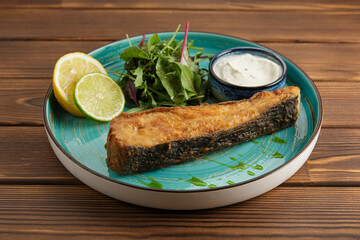 Fried salmon or salmon fish in a plate on a wooden table, a delicious delicacy dish.