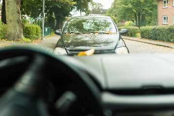 view of a car showing the steering wheel, dashboard, and front panel in focus. Soft natural light highlights the modern design and textures of the vehicle interior, creating a realistic driv