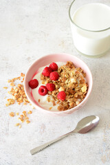 Healthy Breakfast Bowl with Yogurt, Granola and Raspberries and a teaspoon vertical