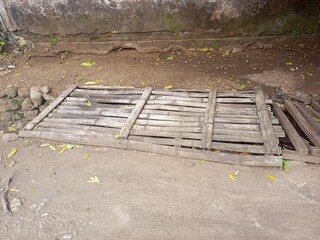 Weathered bamboo platform lying on the dirt ground outdoors