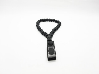 Black prayer beads featuring a decorative pendant are displayed against a clean white background offering a simple studio shot ideal for showcasing religious items or cultural artifacts.