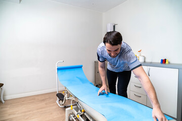 Male physiotherapist preparing examination table for treatment