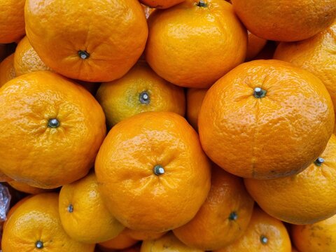 Fresh ripe oranges stacked inp a vibrant display, highlighting bright color and natural texture