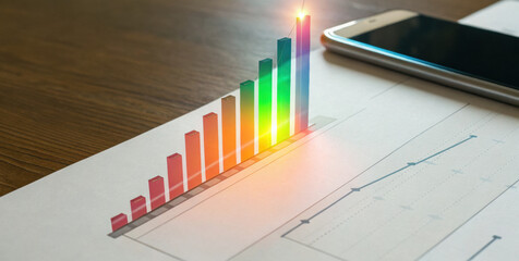 Glowing bar graph emerging from paper, colorful growth chart, business analytics, smartphone nearby, financial report with rising trend