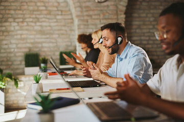 Collaborative Office Team with Headsets Working Together on Laptops in a Modern Open Workspace