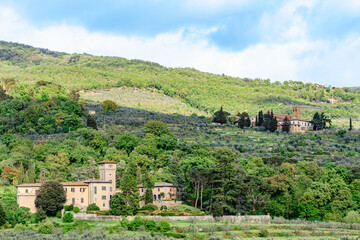 Stunning view of rolling hills with olive groves and historic buildings in Tuscany, Italy