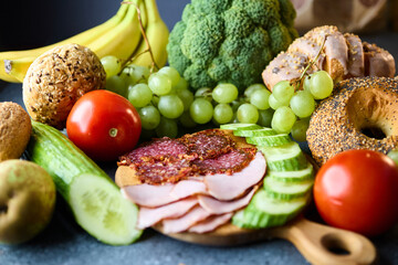 Healthy food composition with ham salami cucumber grapes bananas pears and broccoli