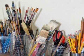 Various professional used paint brushes and artists equipment in the jars