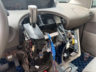 Car dashboard disassembled for electrical repair and diagnostics. Exposed wires, connectors and tools visible inside the vehicle interior․
