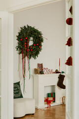 Minimalist corner with a Christmas wreath, candles, and small gifts, festive home styling in warm...