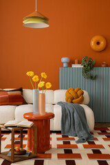 Cozy interior with a white sofa, orange wall, and soft pillows in earthy shades. Stylish...