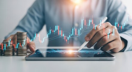 Person analyzing stock market data on tablet with coins and candlestick chart overlay