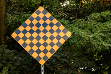 A yellow and black checkered sign warning of a physical hazard, such as the road ending, a sharp turn, or a dead end.