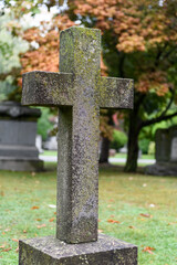 Upright, stone cross monument covered with textured, colorful lichen growth.