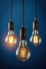 Three vintage edison filament light bulbs hanging against a dark blue background